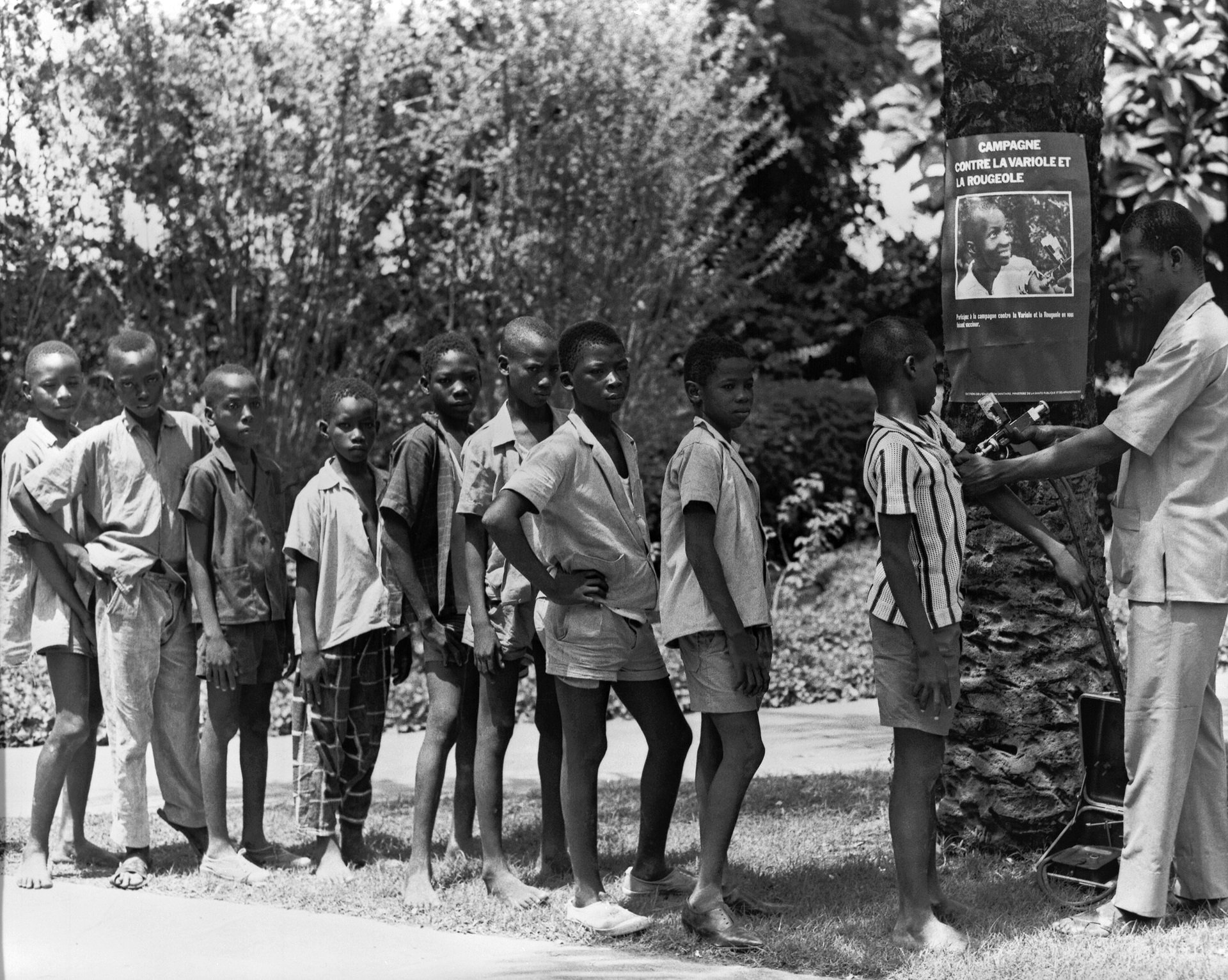 Boys standing in line awaiting smallpox and measles vaccinations